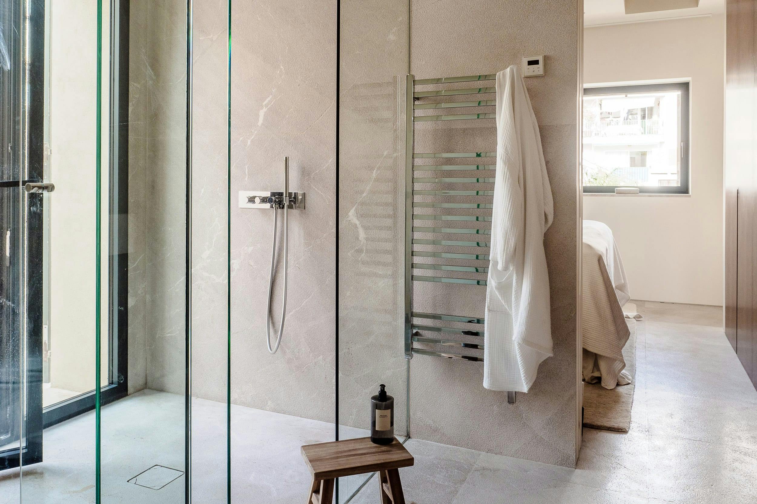 The image features a modern, clean bathroom with a glass shower stall, a towel rack, and a towel on the rack.