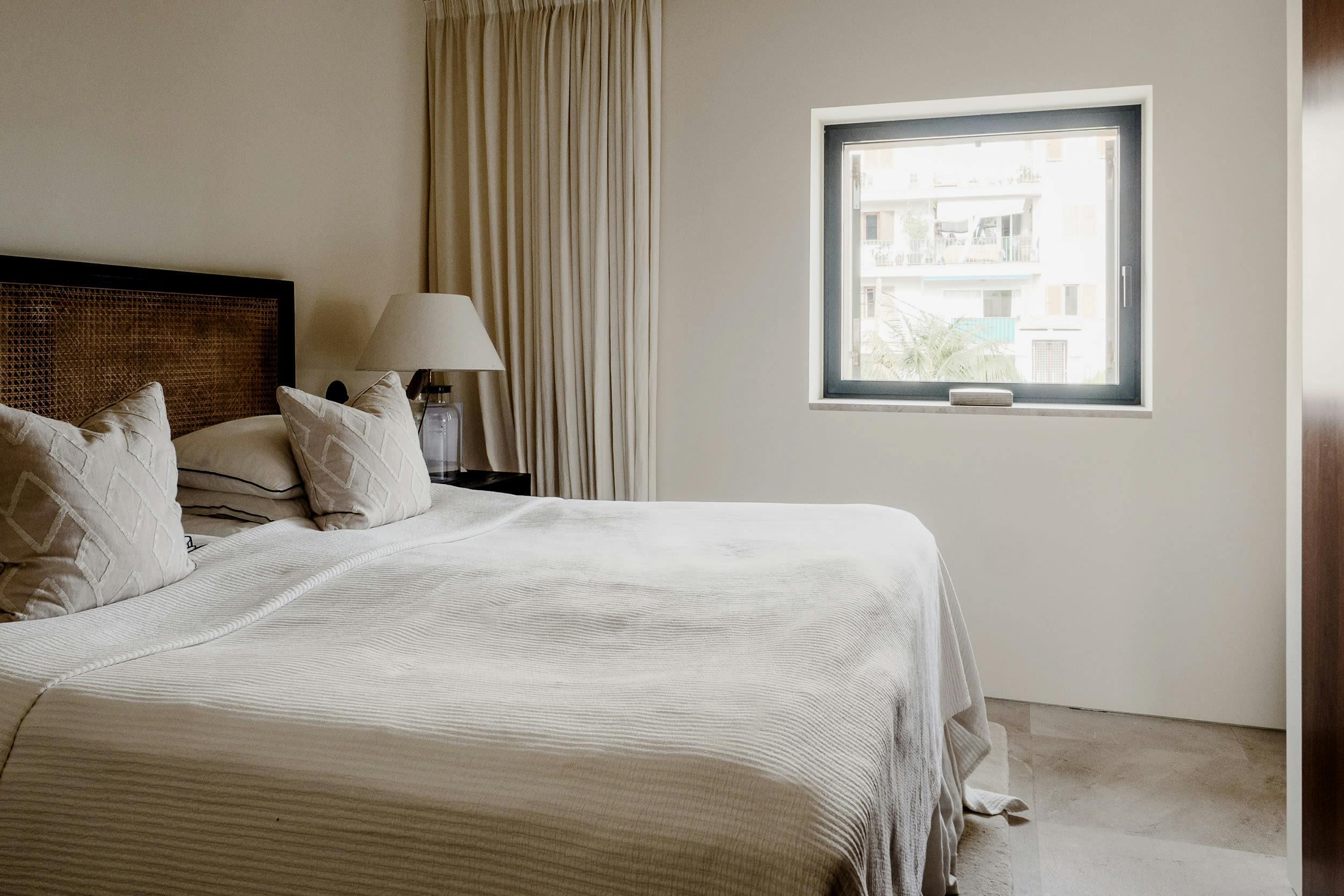The image features a large, neatly made bed with white sheets and pillows in a hotel room.