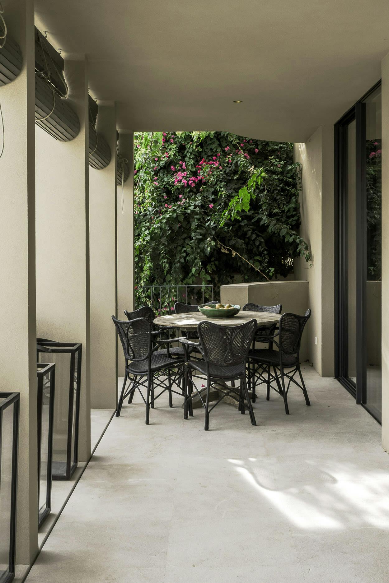 The image features a patio area with a table and chairs, a dining table, and a potted plant.